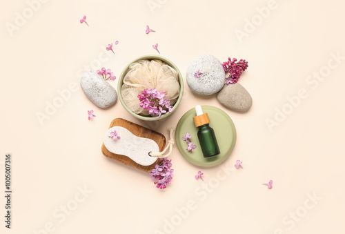 Foot file with bottle of cosmetic oil, loofah and lilac flowers on beige background