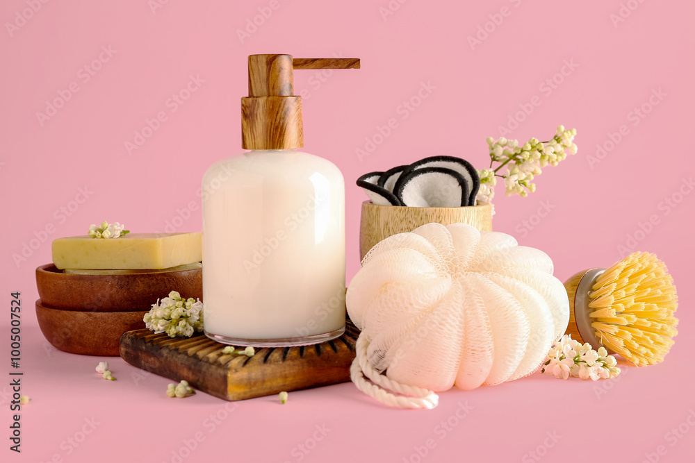 Soap dispenser with white lilac flowers, loofah and brush on pink background Soap dispenser with white lilac flowers, loofah and brush on pink background