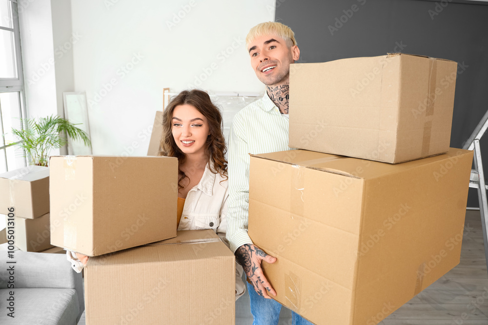 Young couple with cardboard boxes in room on moving day Young couple with cardboard boxes in room on moving day