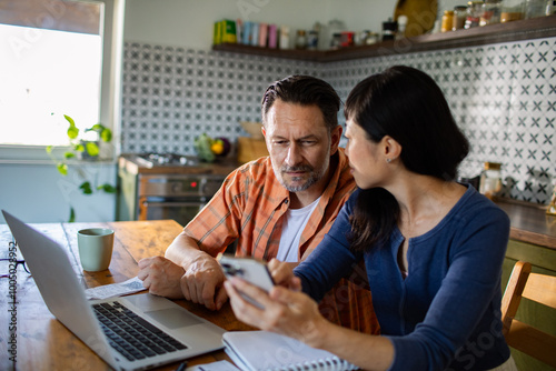 Couple reviewing documents together while using laptop at home