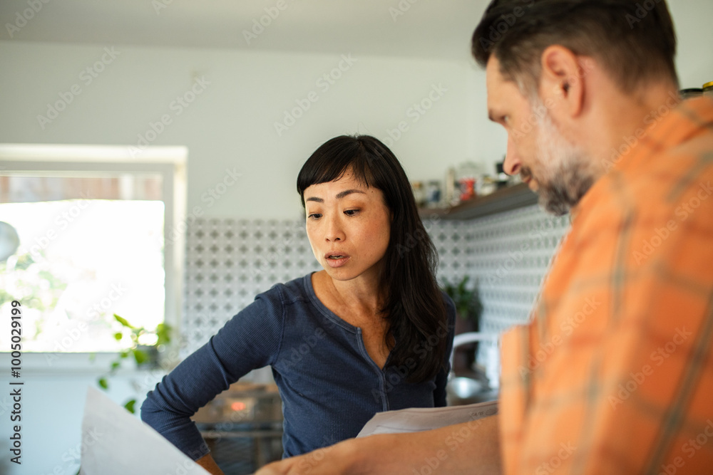 Couple having serious conversation about bills in kitchen at home Couple having serious conversation about bills in kitchen at home