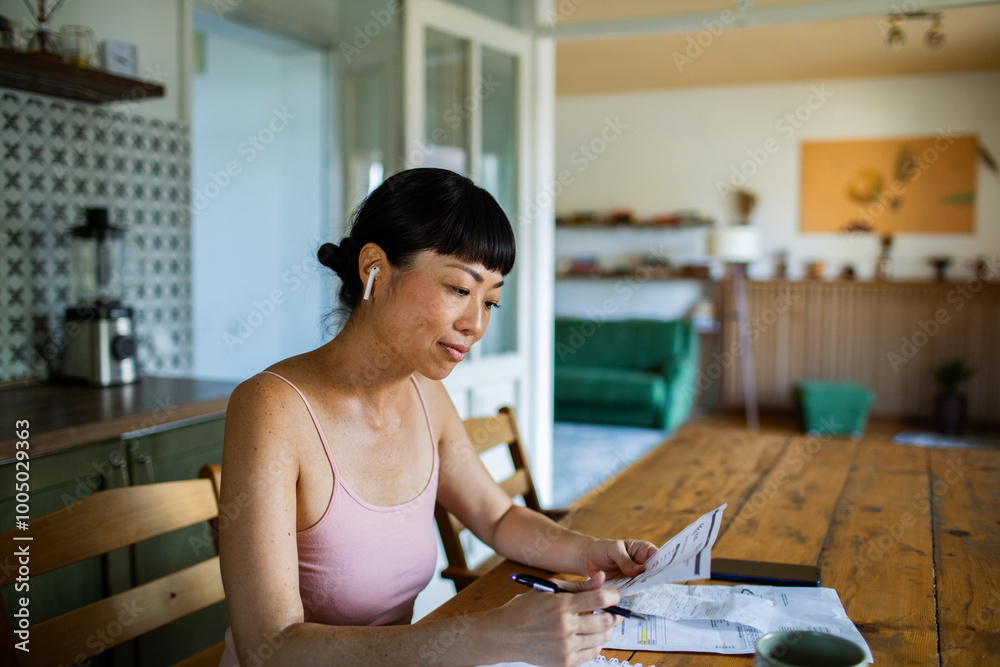 Stressed woman reviewing bills and financial documents at home Stressed woman reviewing bills and financial documents at home