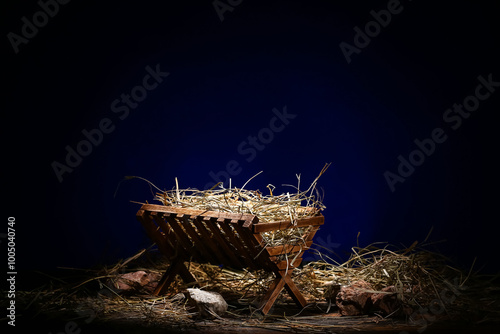 Manger with hay and stones on wooden table against dark blue background