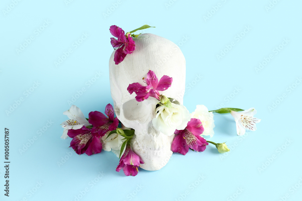 Human skull with beautiful flowers on blue background Human skull with beautiful flowers on blue background
