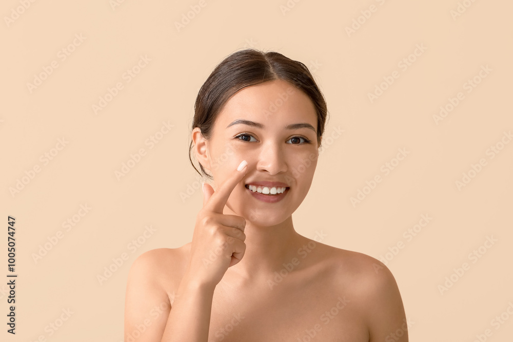 Beautiful Asian woman applying facial cream on beige background, closeup Beautiful Asian woman applying facial cream on beige background, closeup
