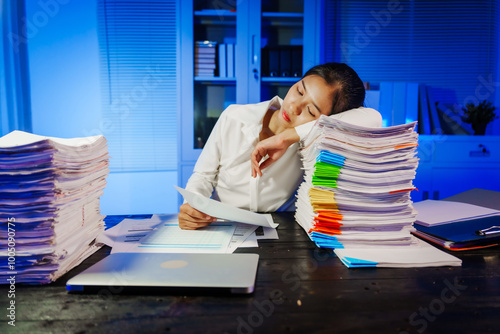 confident Asian businesswoman works late into the night, surrounded by a stack of papers in a busy office. Overtime leads to office syndrome symptoms like neck pain, headaches, and chronic stress. photo