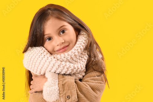 Little girl in winter clothes on yellow background, closeup