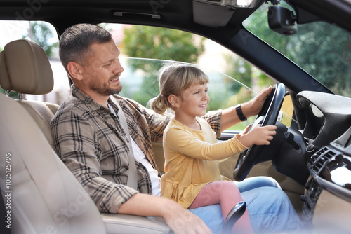 Man with his daughter holding steering wheel inside car