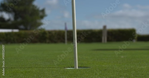 Golf putting green practice shots ball rolls by pin hole close up slow motion
