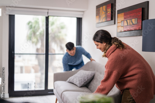 Young married couple moving in their new apartment and placing a sofa in the living room photo