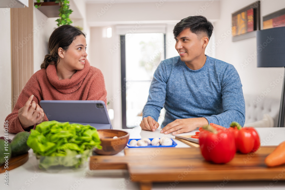 Young couple cooking together following a recipe on tablet Young couple cooking together following a recipe on tablet