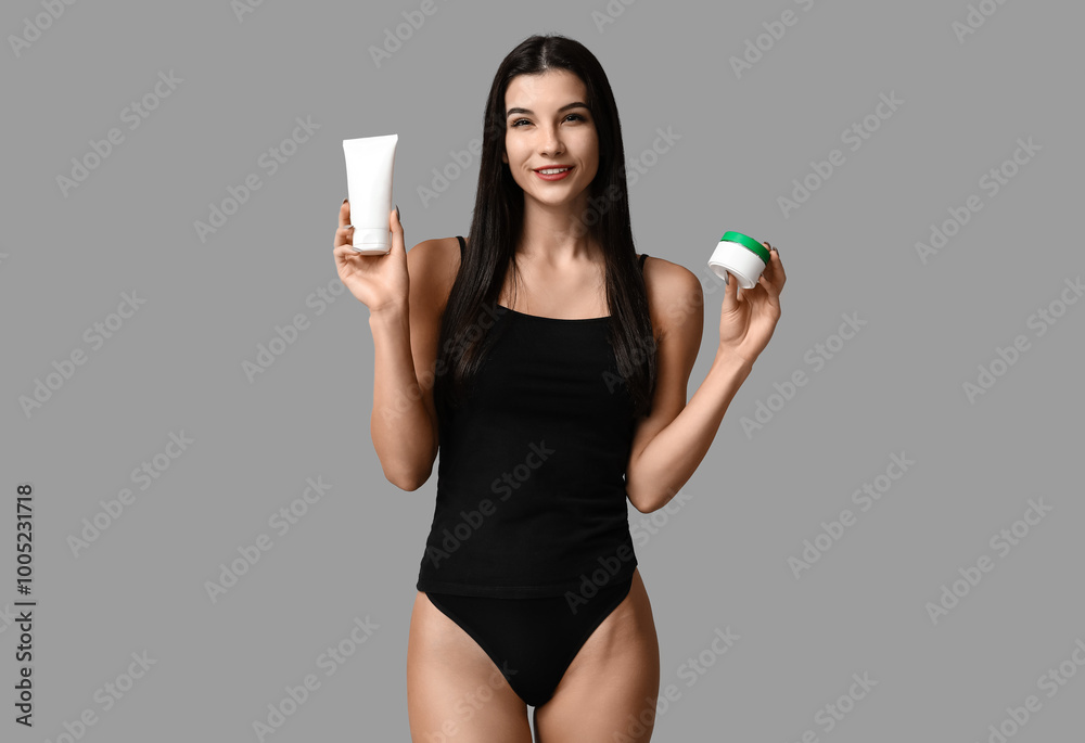 Beautiful young happy woman with bottle and jar of cosmetic product on grey background Beautiful young happy woman with bottle and jar of cosmetic product on grey background