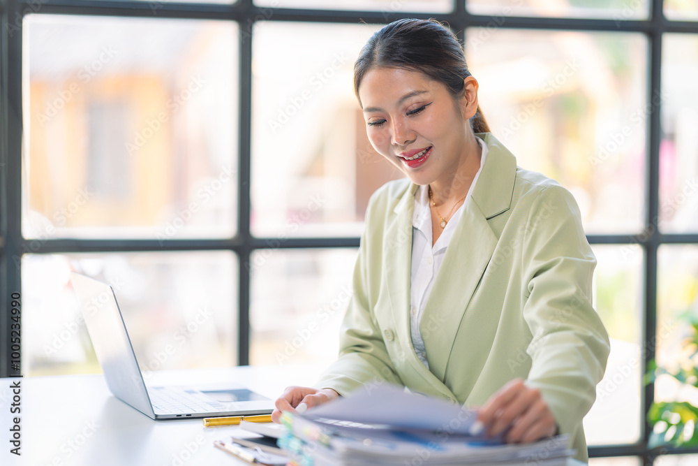 Asian businesswoman sitting at desk and calculating financial graph showing results of her investment. Asian businesswoman sitting at desk and calculating financial graph showing results of her investment.
