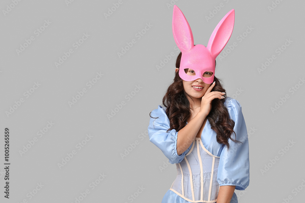 Beautiful young Asian woman in bunny mask on grey background Beautiful young Asian woman in bunny mask on grey background