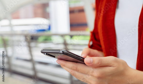 Woman holding smartphone while walking in the urban city. The concept of using the phone is essential in everyday life.