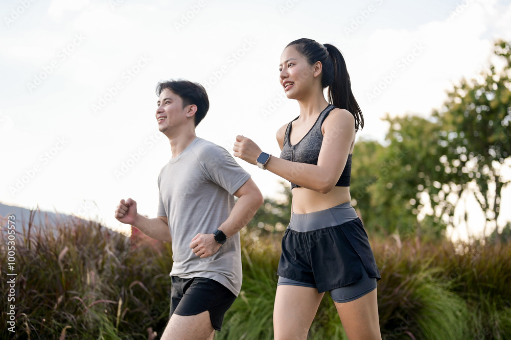 An active, sporty Asian couple in sportswear is enjoying a run together in a park in the morning. An active, sporty Asian couple in sportswear is enjoying a run together in a park in the morning.