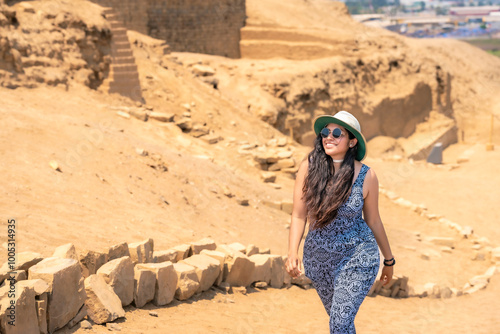 Young Latina woman wearing a hat and sunglasses, hiking through the ancient ruins of Pachacamac in Peru on a sunny day. photo