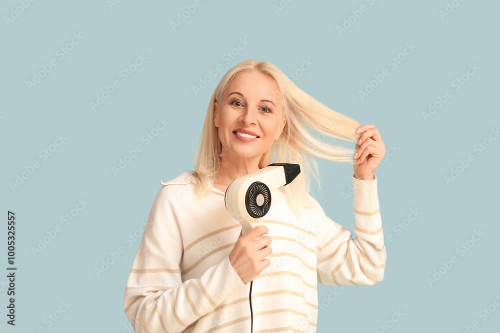 Fototapeta premium Mature woman with hair dryer on color background