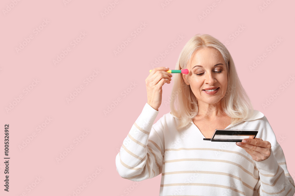 Beautiful mature woman doing makeup on pink background Beautiful mature woman doing makeup on pink background