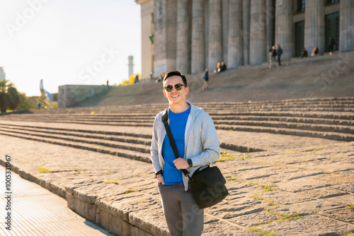 Young Latino man smiling and posing in front of historic architecture at the University of Buenos Aires (UBA), Argentina. photo