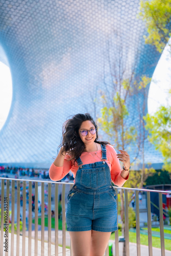 Young Latina woman confidently posing at Museo Jumex, with Soumaya Museum in the background, in Polanco, Mexico City. photo