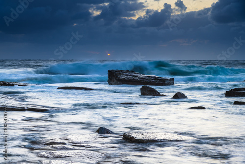 Moody sunrise seascape with clouds at the rocky inlet photo