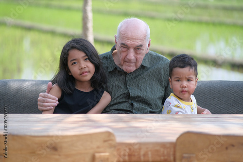 The love of a grandpa sitting on a garden table with his two grand children
