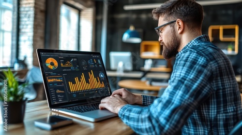 A man in a plaid shirt analyzes data on his laptop.