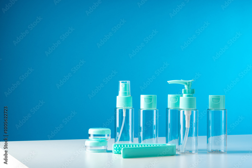 Clear containers for beauty products arranged on a white surface against a bright blue background Clear containers for beauty products arranged on a white surface against a bright blue background