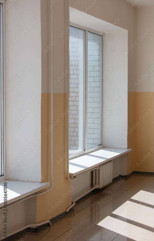 Fototapeta premium A window with a white frame and a white sill sits in a room with a yellow wall
