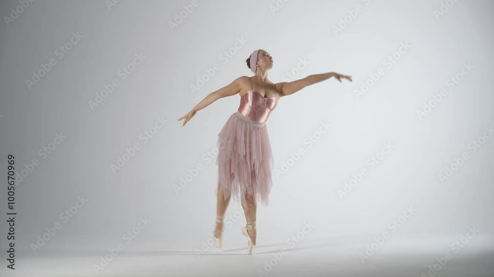 Graceful ballerina in a pink tutu dance and perform dramatic choreographic elements on a white background, windy and beautiful dance. Graceful ballerina in a pink tutu dance and perform dramatic choreographic elements on a white background, windy and beautiful dance.