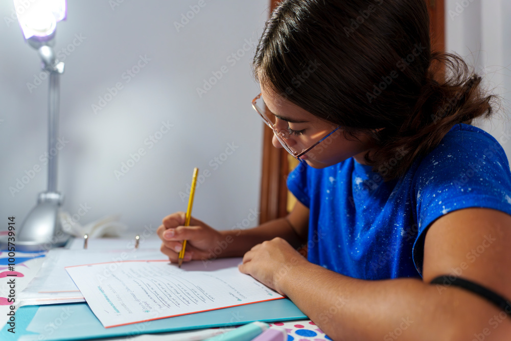 Focused Girl Studying and Writing in Notebook with Pencil at Home Desk