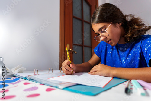 Young Girl Focused on Homework, Writing in Notebook at Study Desk