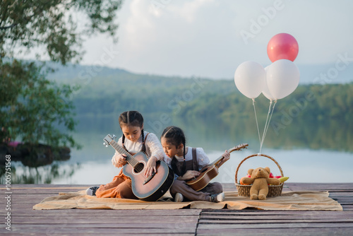 Two Asian girls sing and laugh happily on a wooden bridge by the lake.