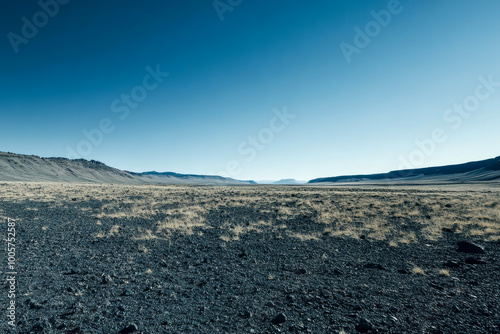 A desolate, barren landscape with a clear blue sky. The sky is the only color in the image, and it is the dominant feature. The emptiness of the landscape