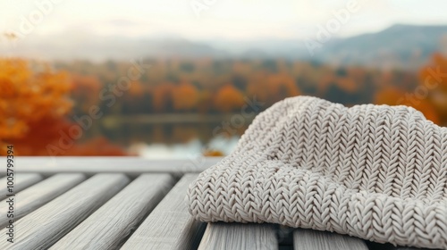 Cozy knit hat on wooden table with autumn scenery in the background. photo