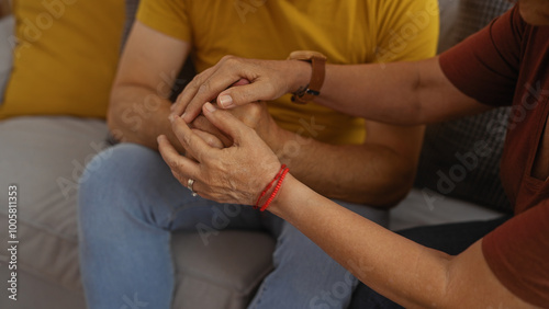 Middle aged couple sharing a moment of love and support holding hands in a cozy living room of an apartment