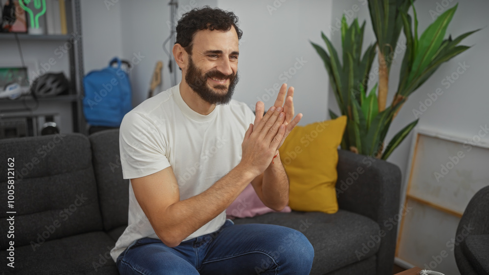 Smiling man with beard clapping hands in modern living room Smiling man with beard clapping hands in modern living room