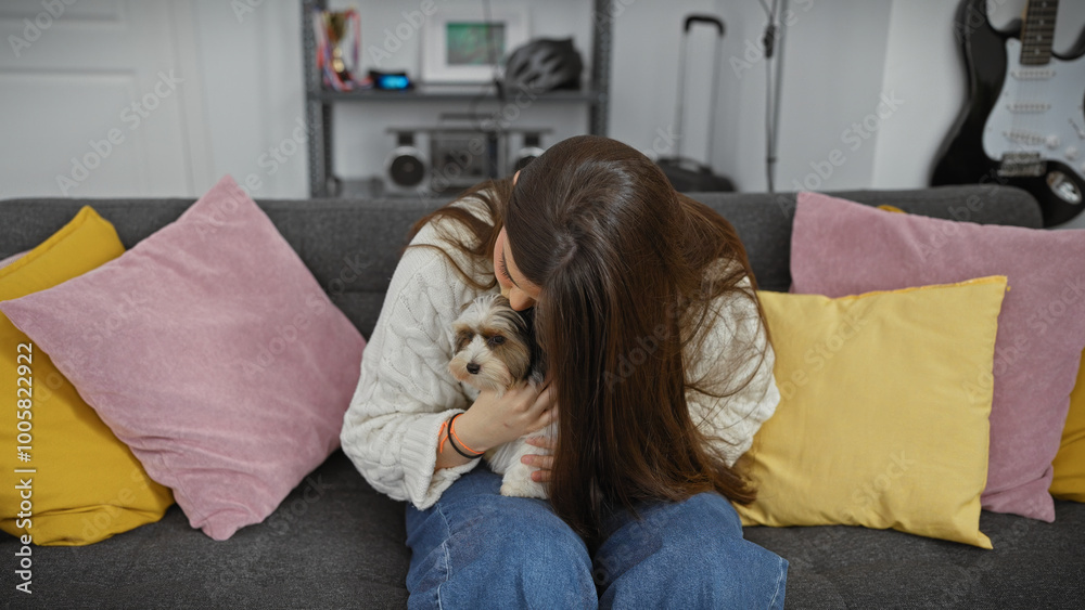 A young hispanic woman lovingly hugs her biewer yorkshire terrier at home on a cozy sofa. A young hispanic woman lovingly hugs her biewer yorkshire terrier at home on a cozy sofa.