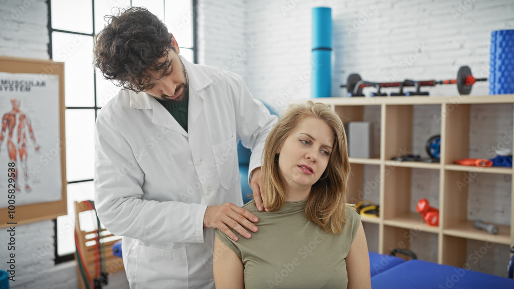 Physiotherapist man treating shoulder of woman patient in clinic.