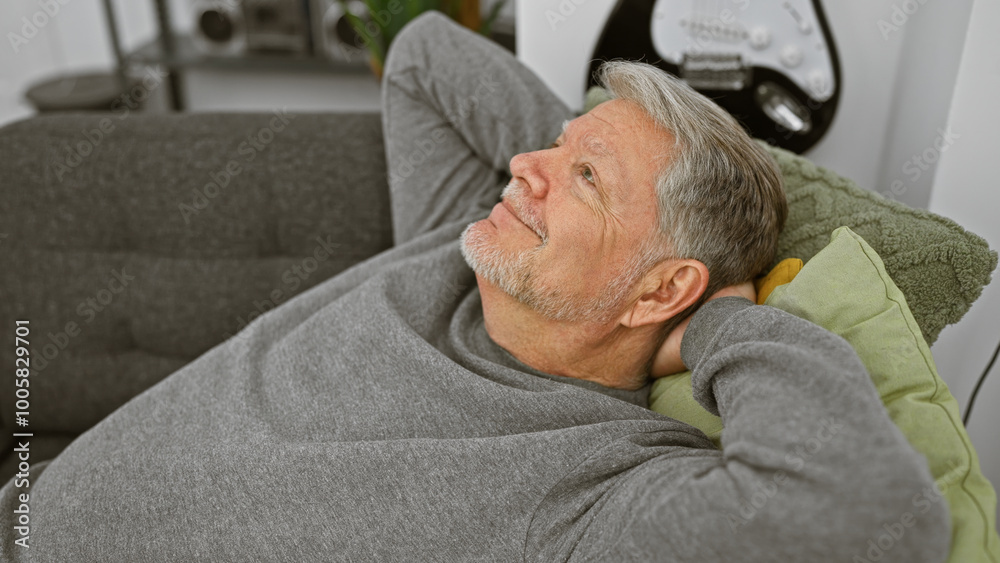 Obraz premium A relaxed senior man with grey hair rests on a couch in a cozy living room, embodying tranquility and comfort.