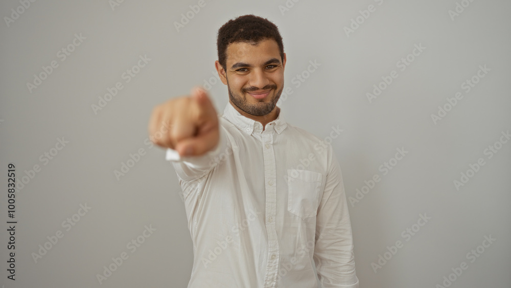 Young hispanic man pointing at camera with a confident smile, isolated over a white background Young hispanic man pointing at camera with a confident smile, isolated over a white background