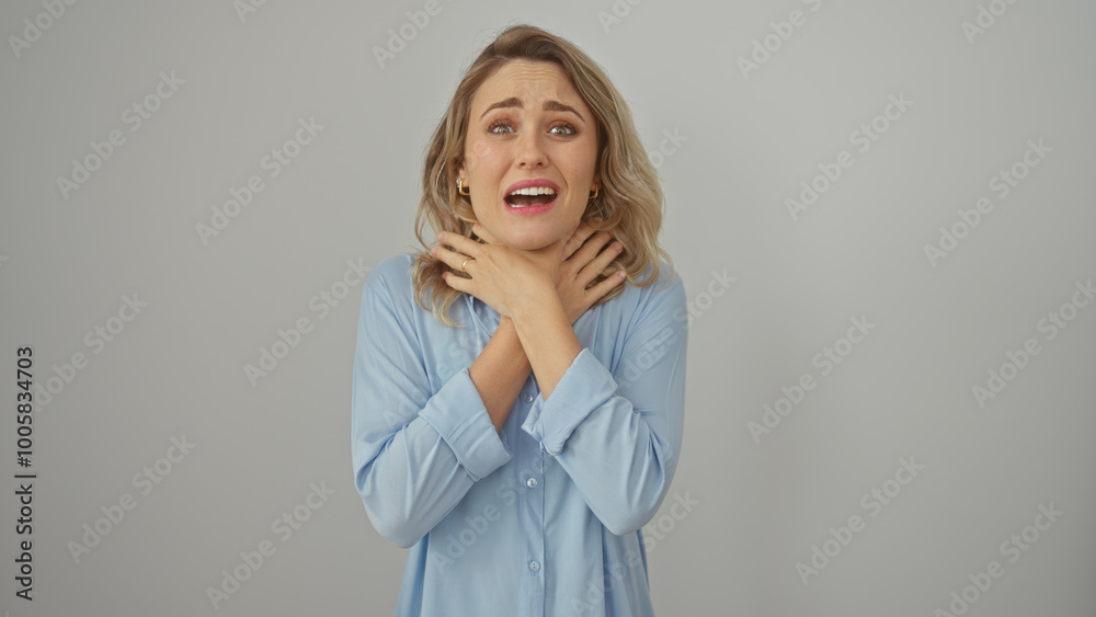 Anxious young caucasian woman grasping her neck against a plain white background, portraying stress or discomfort. Anxious young caucasian woman grasping her neck against a plain white background, portraying stress or discomfort.