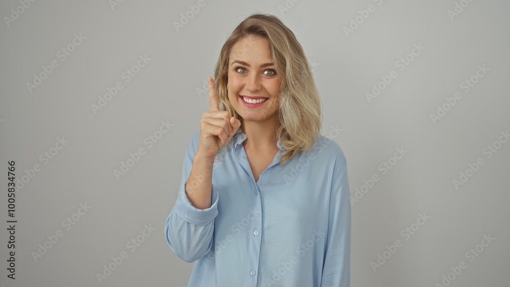 Caucasian woman with blonde hair pointing upwards, expressing idea gesture on a white background Caucasian woman with blonde hair pointing upwards, expressing idea gesture on a white background
