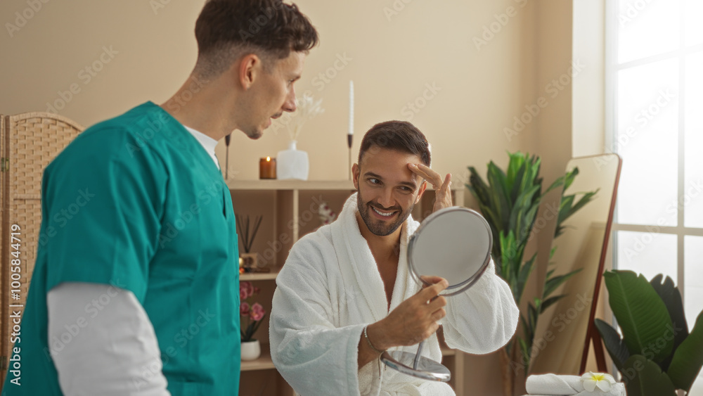 Therapist interacting with man patient in spa wearing robe holding mirror interior wellness center