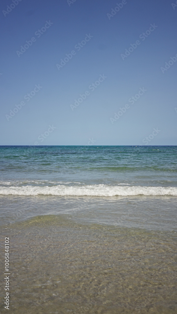 Tranquil beach with gentle waves meeting the sandy shore under a clear blue sky creating a peaceful coastal scene perfect for relaxation. Tranquil beach with gentle waves meeting the sandy shore under a clear blue sky creating a peaceful coastal scene perfect for relaxation.