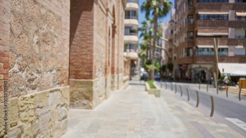 Blurred street view with historic brick building, modern apartments, and palm trees creating a vibrant urban environment in the sunny outdoors