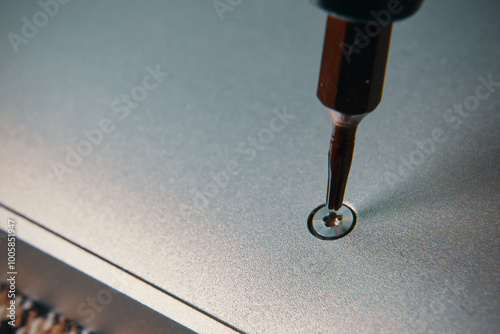 A detailed closeup view of a screwdriver meticulously aligning a screw into a metallic surface for precise assembly
