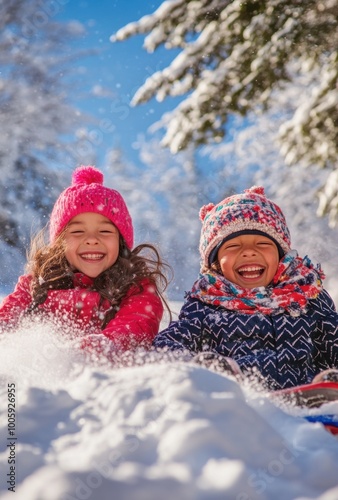 Two happy children play in the snow, dressed for winter in colorful coats and hats. They laugh as they slide down an icy hill on a pile of fresh white snow under a clear blue sky.