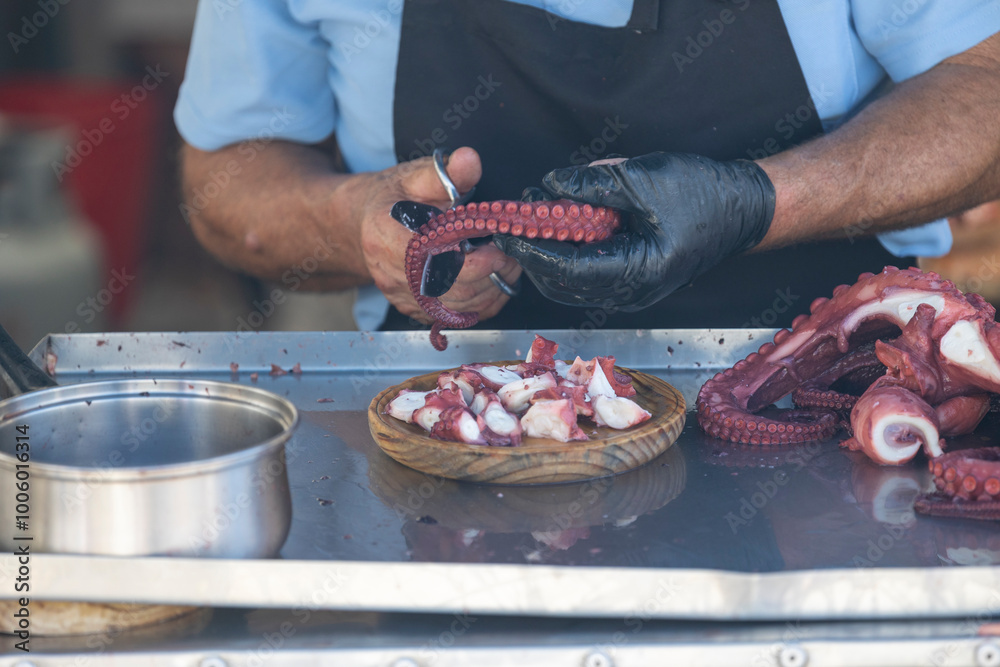 A person is skillfully slicing fresh octopus tentacles at a street market stall, showcasing culinary expertise and attention to detail in seafood preparation. A person is skillfully slicing fresh octopus tentacles at a street market stall, showcasing culinary expertise and attention to detail in seafood preparation.